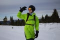 Man in bright acid green snowboard suit, black warm gloves, orange ski goggles, black helmet and backpack. skier outfit Royalty Free Stock Photo