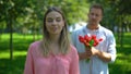 Man bringing girl bunch of flowers, annoyed lady rolling eyes, unrequited love