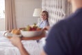 Man Bringing Woman Breakfast In Bed To Celebrate Wedding Anniversary Royalty Free Stock Photo