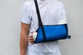 Man with broken arm wrapped medical cast plaster and blue bandage. Fiberglass cast covering the wrist, arm, elbow after sport Royalty Free Stock Photo