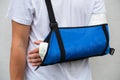 Man with broken arm wrapped medical cast plaster and blue bandage. Fiberglass cast covering the wrist, arm, elbow after sport