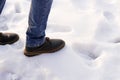 Man in brown boots and blue jeans desided to make first step to obscurity on the snow. Copy space. First step after snow