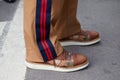 Man with brown decorated shoes and trousers with blue and red stripe before fashion Albino Teodoro show,