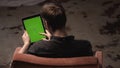 Man with brown hair in black shirt sliding on green mock-up screen of digital tablet computer with tracking marks. Stock