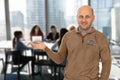 A man in a brown shirt with a flag patch on it is standing in front of a group o Royalty Free Stock Photo