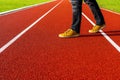 Man in brown sneakers and black jeans walk across the running track