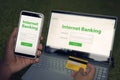 Man browsed homepage of internet banking service on his smartphone and laptop holding credit card. Online payment mobile