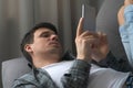 Man is browsing smartphone finding a woman on dating site online lying on sofa.