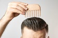 Man brushing his hair with a wooden comb and show how to take care about hair at home. Modern and stylish haircut after Royalty Free Stock Photo