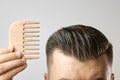 Man brushing his hair with a wooden comb and show how to take care about hair at home. Modern and stylish haircut after Royalty Free Stock Photo