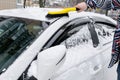 Man brushing snow and ice from car roof with brush. Person cleaning fresh snow after snowstorm from sedan car in the winter