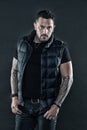 Man brutal unshaven hispanic appearance tattooed arms. Bearded man posing with tattoos. Macho unshaven brutal wear vest