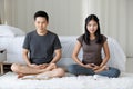 Man Buddhist sitting seside the bed and doing meditation while woman laying on the floor beside the bed and reading book happiness