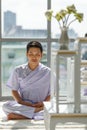 Man Buddhist in white dress sitting and doing meditation in front of set of altar table with buddha image. Idea for ritual and Royalty Free Stock Photo