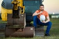 Man builder near excavator. Builder worker with excavator. Builder in helmet. Worker in hardhat. Portrait mechanical