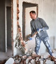 Male worker breaking wall with sledgehammer in apartment. Royalty Free Stock Photo