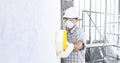 Man builder using a sponge on  wall professional construction worker with mask, safety hard hat, gloves and protective glasses. Royalty Free Stock Photo