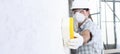 Man builder using a sponge on wall professional construction worker with mask, safety hard hat, gloves and protective glasses.