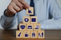 Man building pyramid of cubes with different icons at wooden table, closeup. Insurance concept Royalty Free Stock Photo