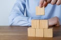 Man building pyramid of cubes on wooden table, closeup. Space for text Royalty Free Stock Photo