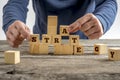 Man building a structure of wooden cubes while assembling word S