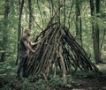 Man building a survival shelter in the forest. Shelter in the woods from tree branches