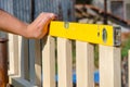 Man building a wooden fence and checking with spirit level. Close up of his hand and the tool in a DIY concept.