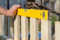 Man building a wooden fence and checking with spirit level. Close up of his hand and tool. Royalty Free Stock Photo