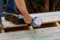 Man building a wooden patio with hammering screwing together beams Royalty Free Stock Photo