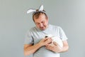 A man with bunny ears and a gray T-shirt is holding a white rabbit. Royalty Free Stock Photo