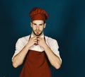 Man in burgundy cook hat and apron. Cook works in kitchen. Cuisine and professional cooking concept Royalty Free Stock Photo