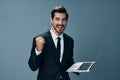 Man business looks into laptop and works online smiling fist up online in business suit video call business negotiations
