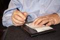 Man in business shirt with wedding ring signs credit card bill at restaurant - close-up of hands and check on black tablecloth - Royalty Free Stock Photo