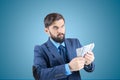 Man in a business suit with banknotes in his hands thinking about finances looks away Royalty Free Stock Photo