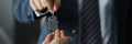 Man in business suit hands overing house keys to woman closeup