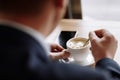 A man in a business suit holds a cup of hot coffee in his hands. Morning businessman in cafe .Copy space
