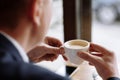 A man in a business suit holds a cup of hot coffee in his hands. Morning businessman in cafe .Copy space