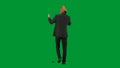 Man in business suit with horse head mask on green studio background. Businessman walking and talking on smartphone Royalty Free Stock Photo