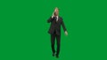 Man in business suit with horse head mask on green studio background. Businessman walking and talking on smartphone Royalty Free Stock Photo