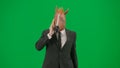 Man in business suit with horse head mask on green studio background. Businessman walking and talking on smartphone Royalty Free Stock Photo