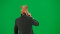 Man in business suit with horse head mask on green studio background. Businessman walking and talking on smartphone Royalty Free Stock Photo