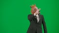 Man in business suit with horse head mask on green studio background. Businessman walking and waving hello. Concept of Royalty Free Stock Photo