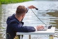 A man in a business suit sits at a white table in a swamp, in an outstretched left hand holds a telephone receiver Royalty Free Stock Photo