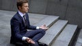 Man in business suit sitting in lotus position, gaining self-control in business