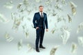 A man in a business suit stands against the background of falling dollars, banknotes are falling from the sky. Business concept, Royalty Free Stock Photo