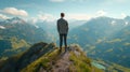 A man in a business suit stands with his back to the camera at the peak of a mountain, with a beautiful mountain Royalty Free Stock Photo