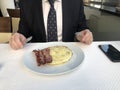 Man in a business suit, tie and white shirt having breakfast, omelet and bacon