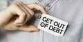 A man businessman in a blue shirt holds a card in a pocket with the text Get Out Of Debt in his hand