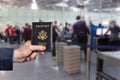 Man businessman in a blue suit with holding american passport in the airport opposite customs control or security service .