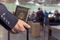 Man businessman in a blue suit with suitcase holding american passport in the airport opposite customs control or security